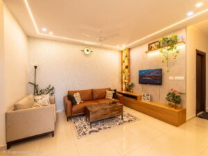 Modern 2 BHK flat living room interior with sofa, wooden TV unit and ambient lighting